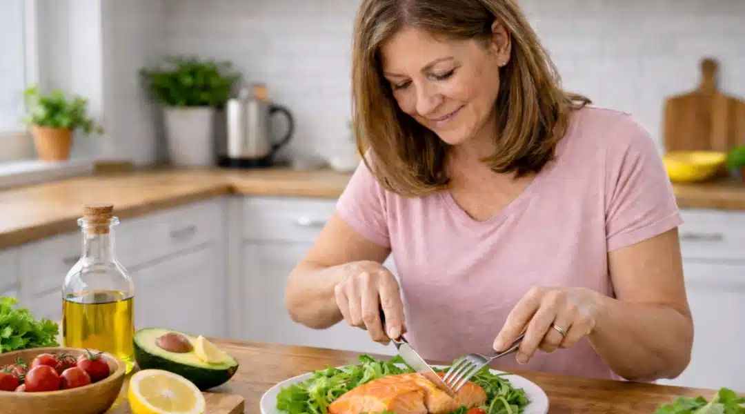 Woman eating salmon and a leafy green salad with avocado